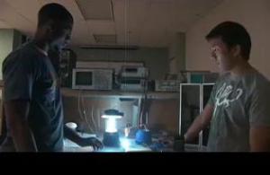 Kansas State University students Tai-Wen Ko and Justin Curry compare light from a florescent lantern (left) with light from their compact solar lantern (right, flat on desk). (Credit: Image courtesy of Kansas State University)